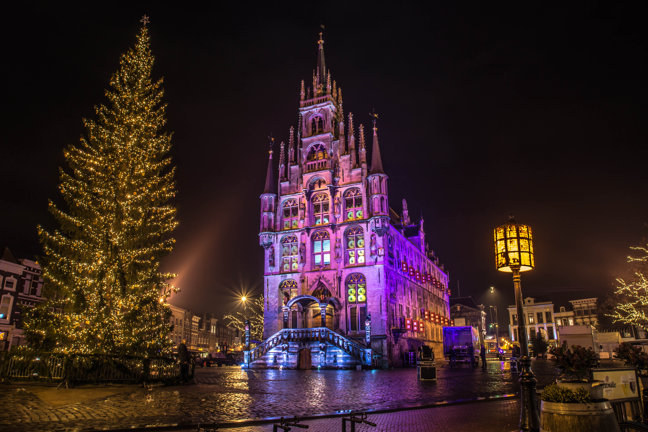 Gothic town hall of Gouda lit up at night beside a tall illuminated Christmas tree